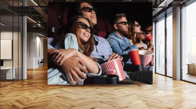 Loving couple sitting in cinema watch film and hugging Wall mural