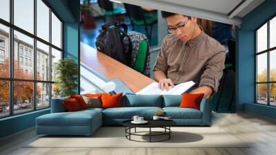 Male student reading book in classroom Wall mural