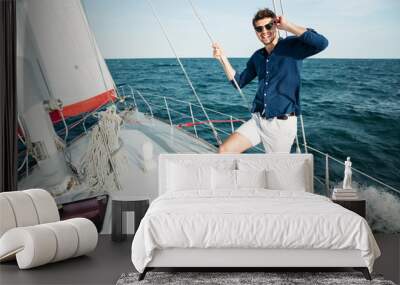 Man looking forward and smiling while standing on the yacht Wall mural