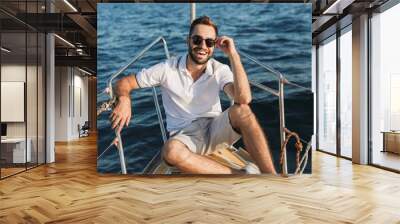 Man outdoors posing on yacht in sea. Wall mural