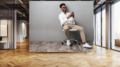 Man sitting in a chair and holding mobile phone Wall mural