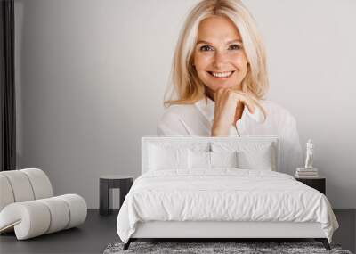 Mature blonde woman wearing shirt smiling and looking at camera Wall mural