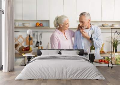 Mature happy loving couple standing at the kitchen drinking wine Wall mural