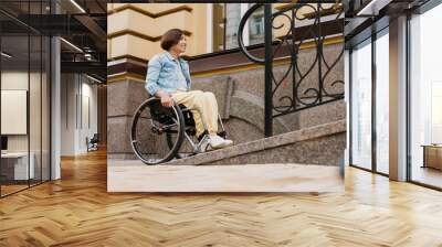 Mid aged brunette disabled woman sitting in a wheelchair Wall mural