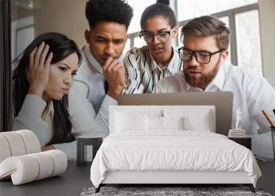 Nervous young business colleagues using laptop computer. Wall mural