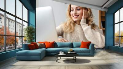 Optimistic young woman using laptop computer. Wall mural