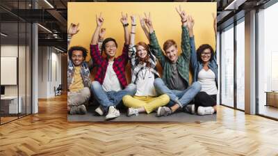 People celebrating success and showing peace sign with raised hands Wall mural