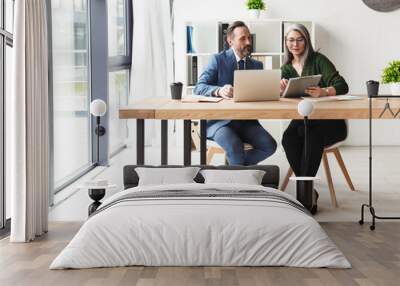 Photo of colleagues talking while working with laptop and documents Wall mural