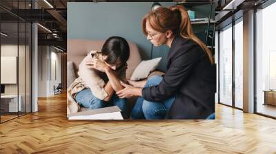 Photo of depressed caucasian woman having conversation with psychologist in room Wall mural