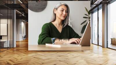 Photo of gray-haired focused businesswoman typing on laptop Wall mural