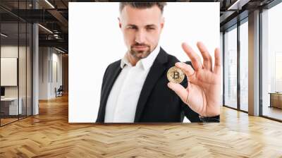 Photo of handsome rich businessman in suit showing golden bitcoin focused on camera, isolated over white background Wall mural