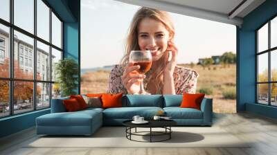 Photo of happy blonde woman holding wine glass and smiling Wall mural