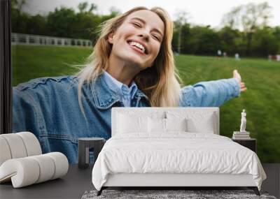 Photo of happy caucasian woman taking selfie photo and smiling while walking in green park Wall mural