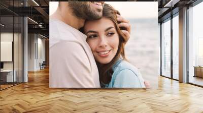 Photo of joyful young couple smiling and hugging while walking Wall mural