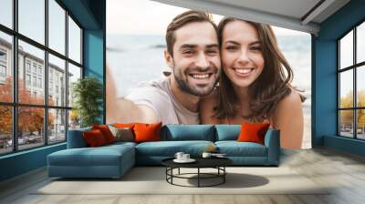 Photo of joyful young couple smiling and taking selfie photo Wall mural