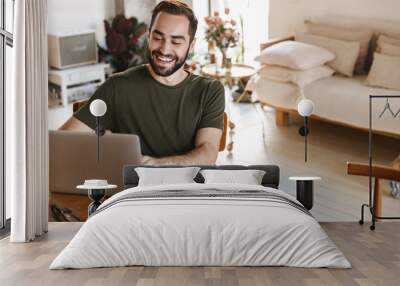 Photo of modern mature man writing down notes on paper and using laptop while working in flat Wall mural