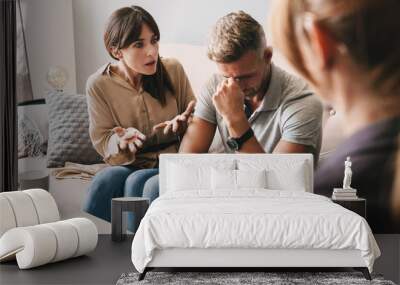 Photo of puzzled annoyed couple having conversation with psychologist on therapy session in room Wall mural