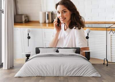 Photo of smiling woman talking on mobile phone while having breakfast Wall mural