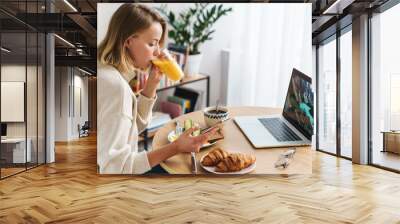 Photo of smiling woman using laptop and cellphone while having breakfast Wall mural