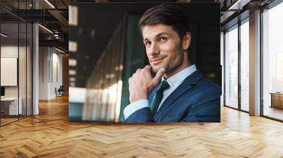 Photo of successful businessman touching his chin while standing outside job center after working in office Wall mural