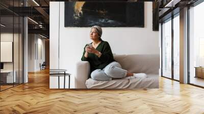 Photo of woman looking aside and using cellphone while sitting Wall mural