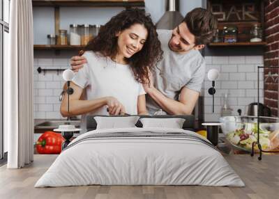 Picture of young couple cooking salat with vegetables together in modern kitchen at home Wall mural