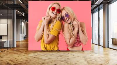 Pleased blonde twins in sunglasses posing together Wall mural