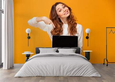 Pleased brunette woman in sweater showing blank laptop computer screen Wall mural