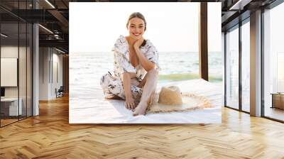 Pleased cheery young beautiful woman at the beach posing in a beautiful sunny morning. Wall mural