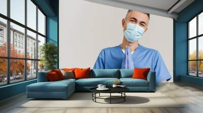 Pleased medical doctor in face mask and gloves holding palms together Wall mural