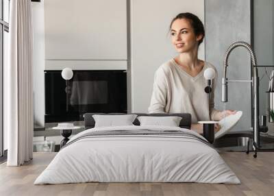 Portrait of a beautiful young woman washing dishes Wall mural