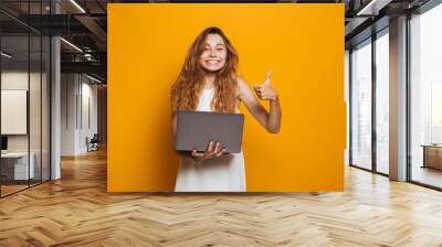 Portrait of a cheerful young girl holding laptop computer Wall mural