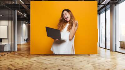 Portrait of a cheerful young girl holding laptop computer Wall mural