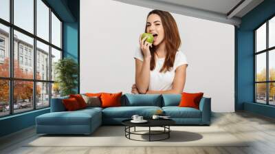 Portrait of a cheerful young woman eating green apple Wall mural