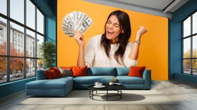 Portrait of a cheerful young woman holding money Wall mural