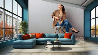 Portrait of a cheery asian woman sitting on a chair Wall mural