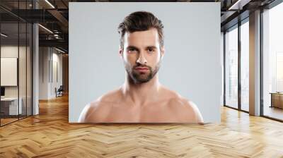 Portrait of a concentrated young bearded man looking at camera Wall mural