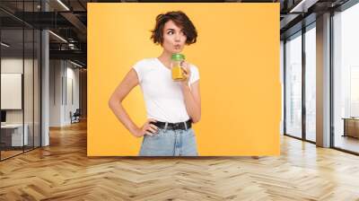 Portrait of a cute casual girl drinking orange juice Wall mural