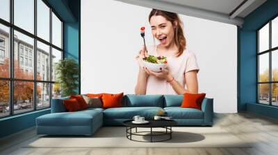 Portrait of a happy playful girl eating fresh salad Wall mural