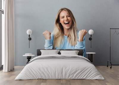 Portrait of a happy young blonde girl celebrating success Wall mural