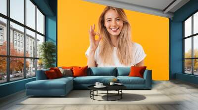 Portrait of a happy young blonde girl showing ok gesture Wall mural