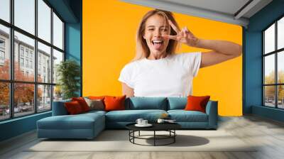 Portrait of a happy young blonde girl showing peace Wall mural