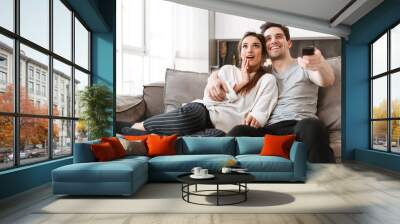 Portrait of a happy young couple relaxing on a couch Wall mural