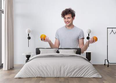 Portrait of a happy young man holding orange Wall mural