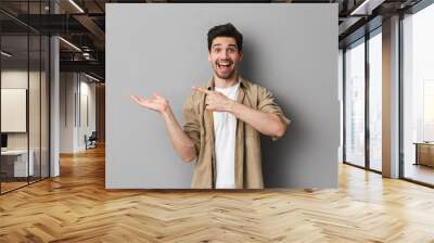 Portrait of a happy young man pointing at copy space Wall mural