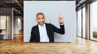 Portrait of a happy young man pointing finger up Wall mural