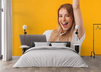 Portrait of a joyful young blonde girl holding laptop Wall mural