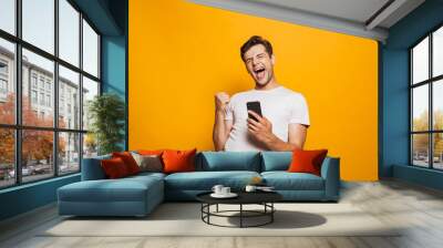 Portrait of a joyful young man holding mobile phone Wall mural