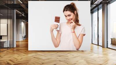 Portrait of a lovely pretty girl holding chocolate bar Wall mural