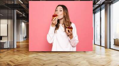 Portrait of a satisfied young woman eating pastry Wall mural